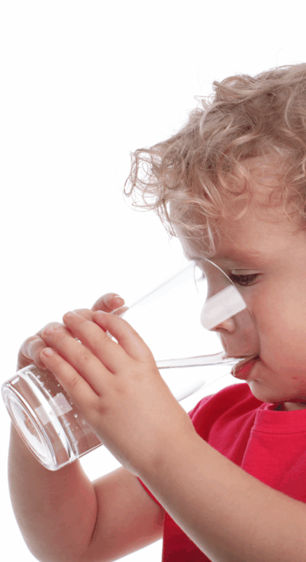 child drinking from a glass of water
