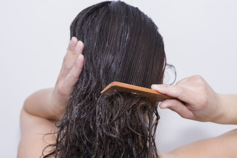 woman combing her hair with a wooden comb