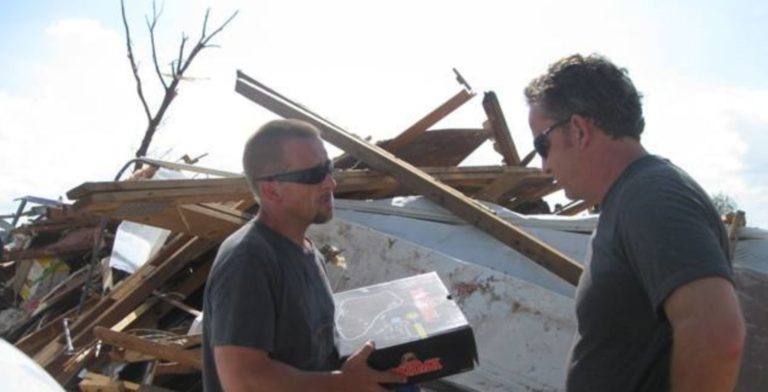 two men talking in the wreckage of a destroyed home
