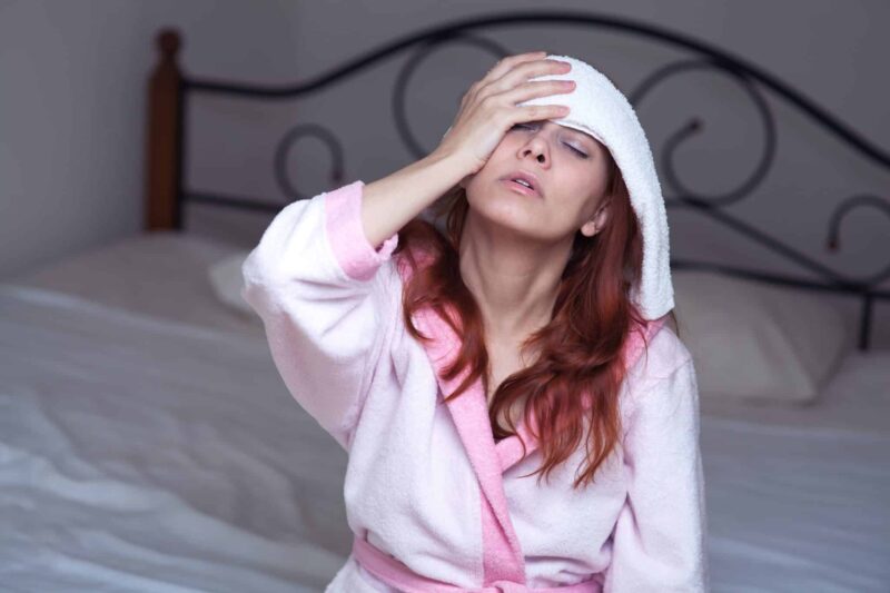 woman that is suffering from a fever so she has out a cool rag on her face