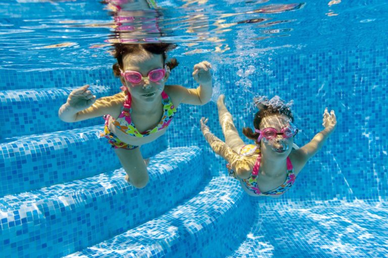 kids looking at the camera under water in a swimming pool