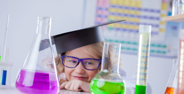 child with a graduate hat having fun in a science class