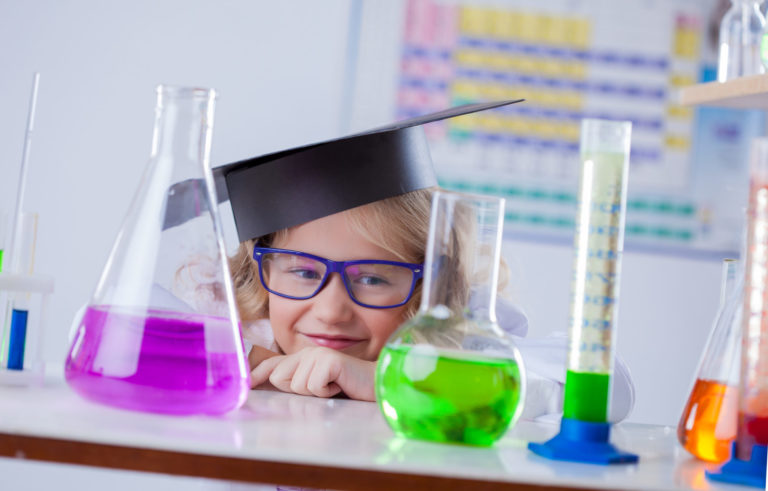 child with a graduate hat having fun in a science class