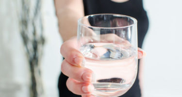 Woman showing a glass of water, closeup