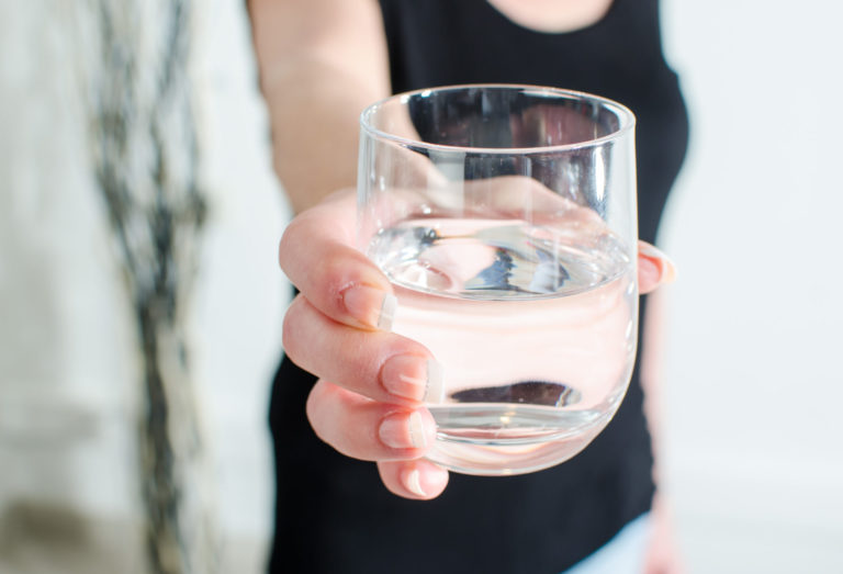 woman showing the camera a glass of filtered purified water