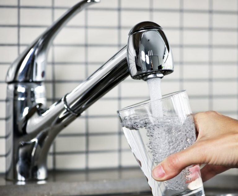 pouring a glass of water from a newly installed faucet