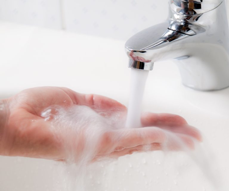 a persons hand being put under warm running water