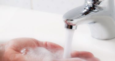 a persons hand being put under warm running water