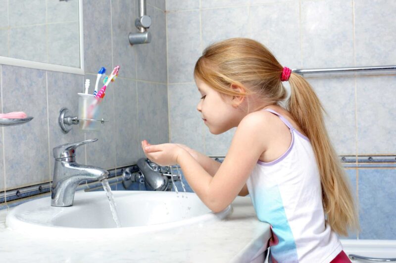 child drinking water by cupping it in her hands