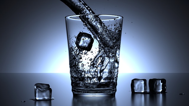 pouring a glass of water with ice cubes in it and around the glass