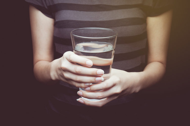 woman holding a glass of water with both hands