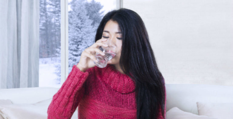 woman drinking a glass of water on a snowy winter day