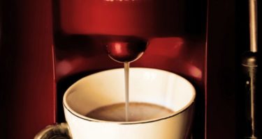 a red coffee machine pouring coffee into a white mug