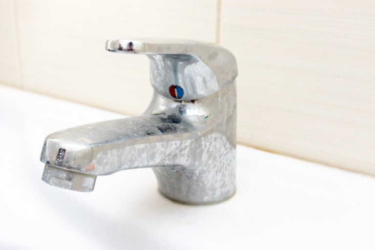 dirty water faucet that has limestone and hard water build up on it