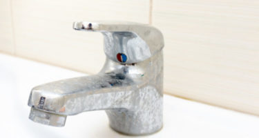 dirty water faucet that has limestone and hard water build up on it