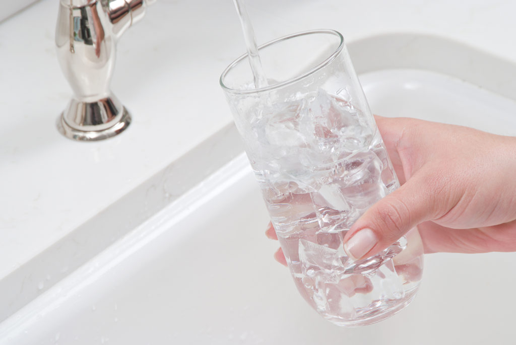 glass of purified water being poured into a glass from the tap