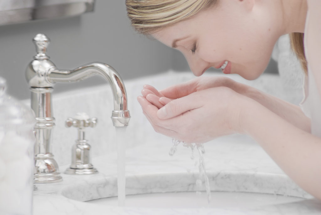 woman cleaning her face with soft purified water by kinetico