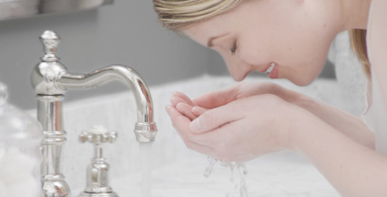 woman cleaning her face with soft purified water by kinetico