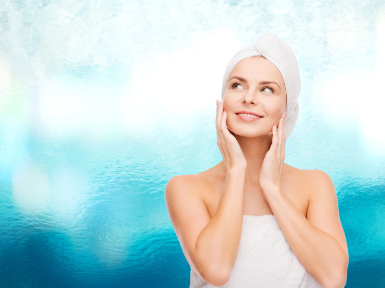 woman wrapped in a white towel with a white towel wrapped around her hair looking up amazed at something