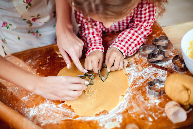 a child making Christmas cookies with her mom