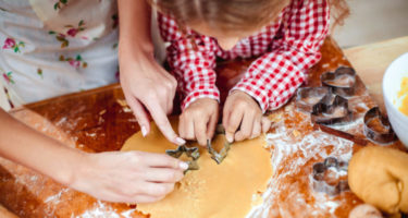 a child making Christmas cookies with her mom