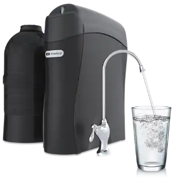 A black water filtration system with a chrome faucet dispensing clear water into a glass, which is filled with bubbles.